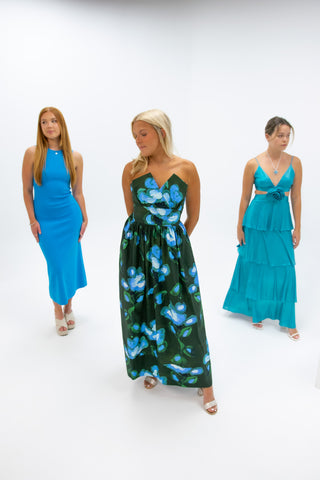 Three woman in maxi dresses posing in front of white backdrop